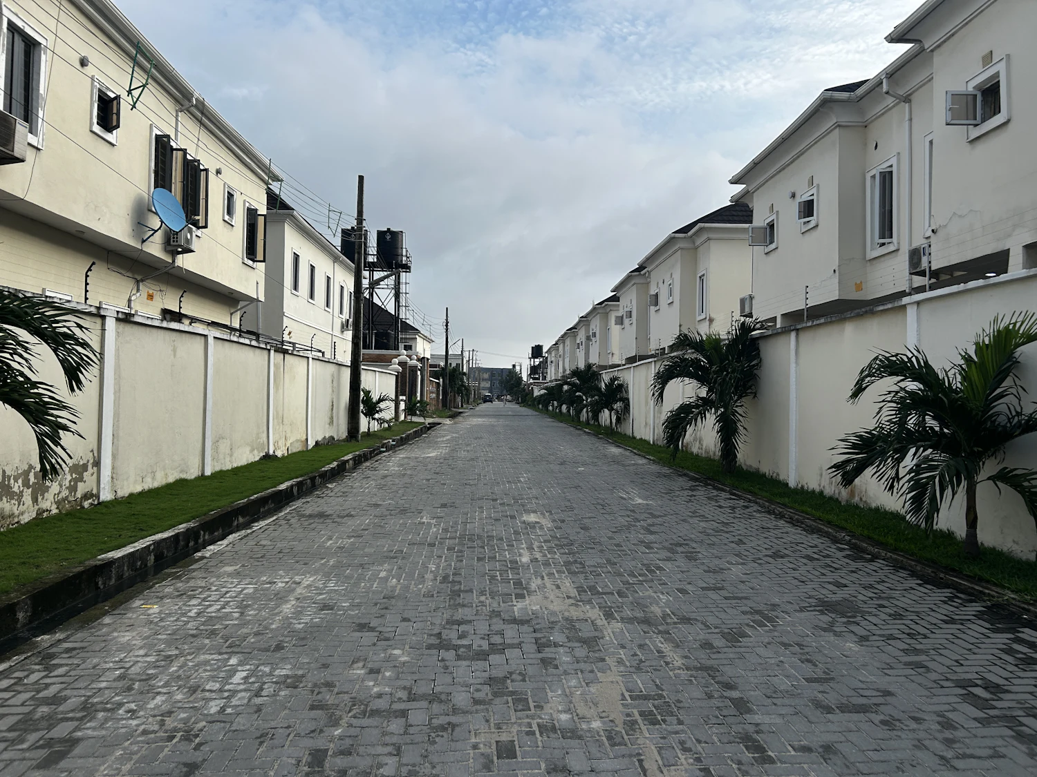 A paved lane with two-storey houses behind walls on both sides