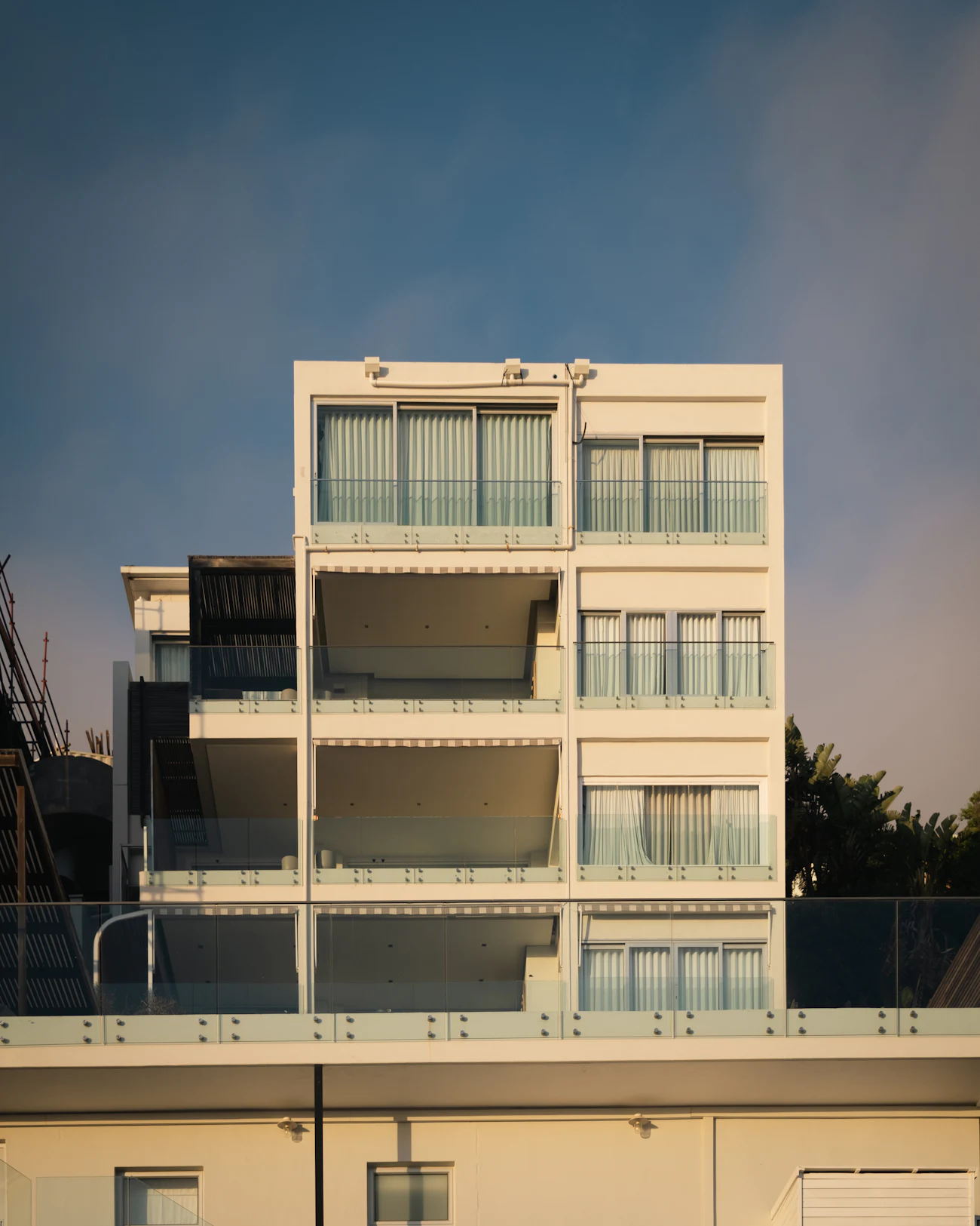 Pale apartment block with glass balconies in evening light