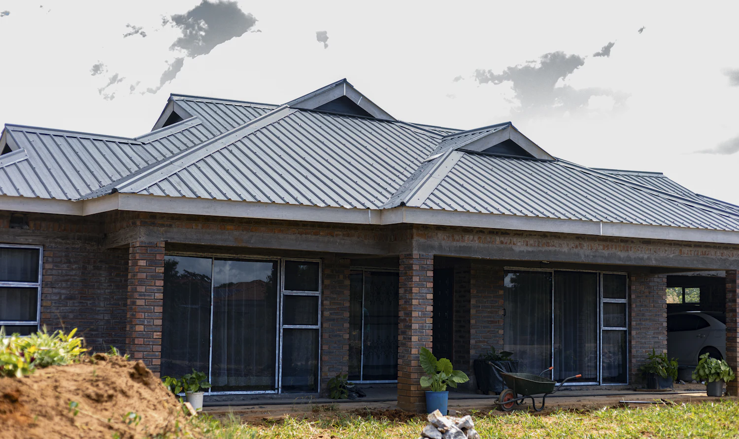 Brick house with a grey metal roof and a covered veranda on brick pillars