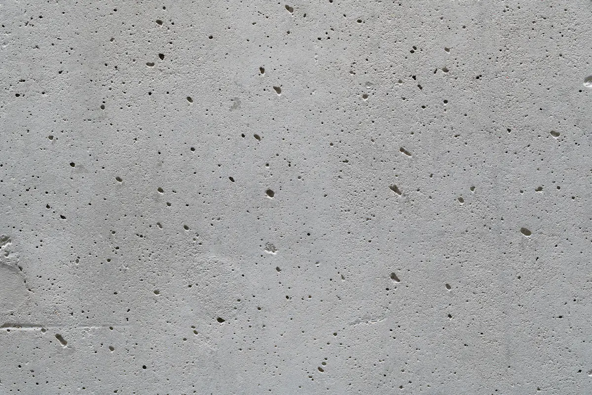 A smooth grey concrete surface with small air holes